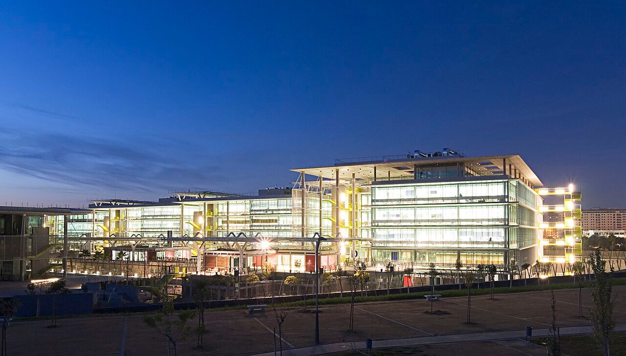Campus Palmas Altas en Sevilla, antigua sede central de Abengoa, con edificios de cristal y estructuras rojas.