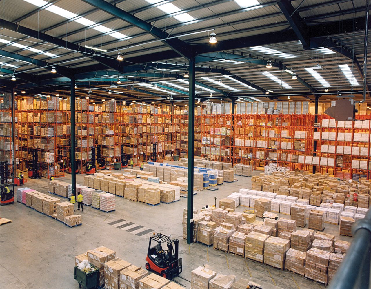 Interior de un almacén moderno con estanterías metálicas de varios pisos llenas de palés europeos.