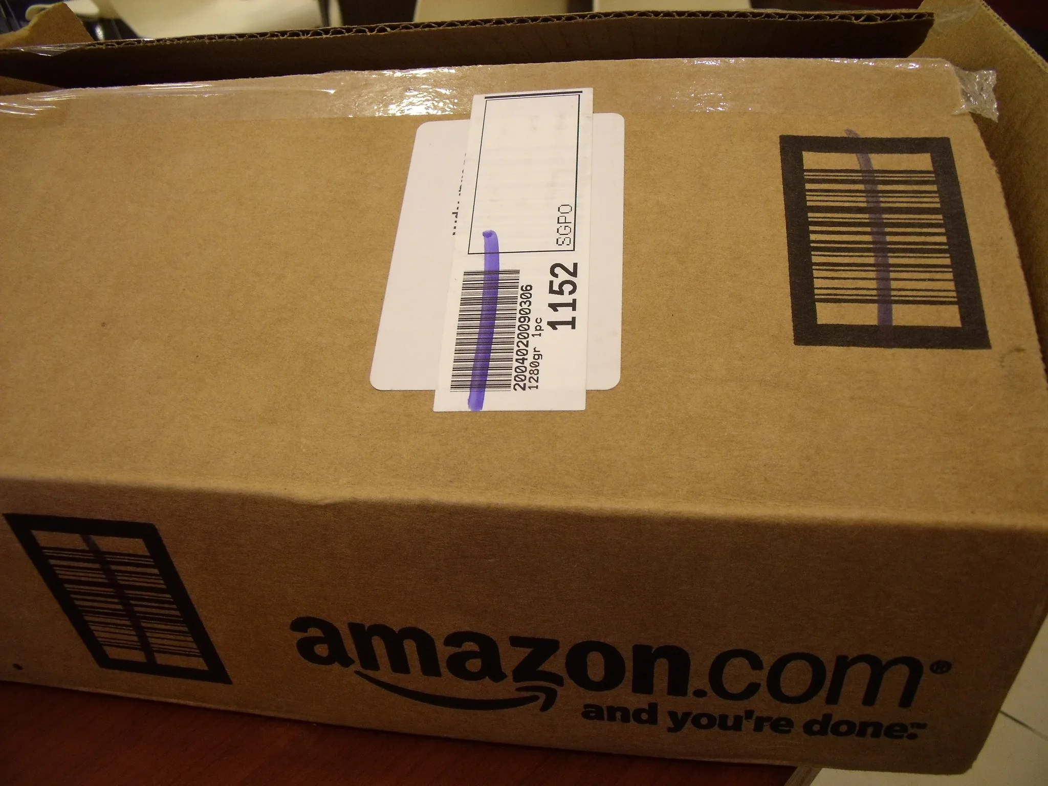 Caja de cartón de Amazon.com con la cinta y el logotipo de la sonrisa visible sobre el embalaje.