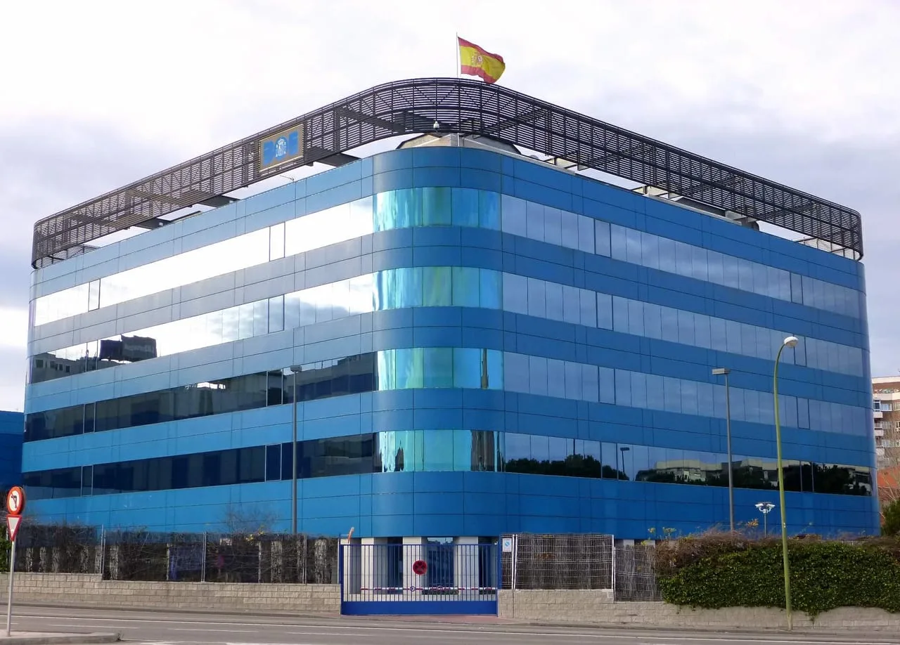 Sede del Boletín Oficial del Estado en Madrid, un edificio acristalado azul con la bandera de España en la cubierta.