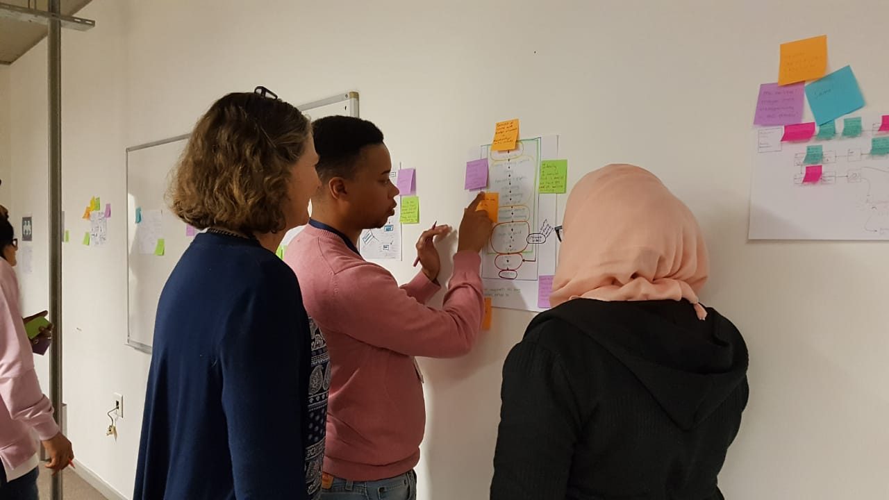Grupo de personas trabajando juntas en un taller alrededor de una mesa con materiales de papel y notas