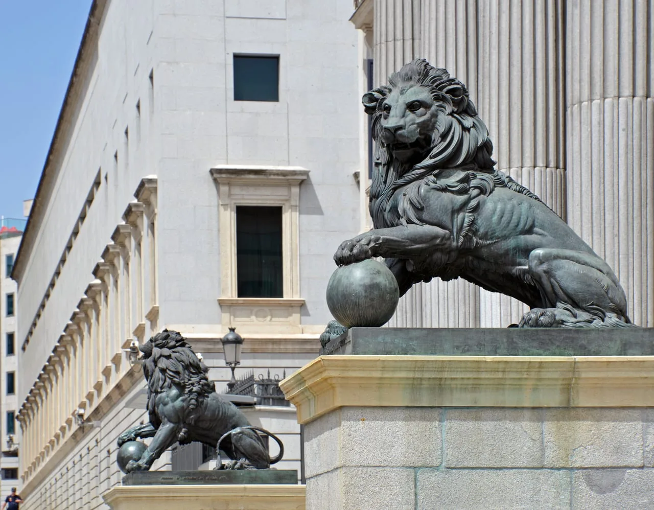 Los dos leones de bronce que flanquean la entrada del Congreso de los Diputados, con las columnas del pórtico detrás.