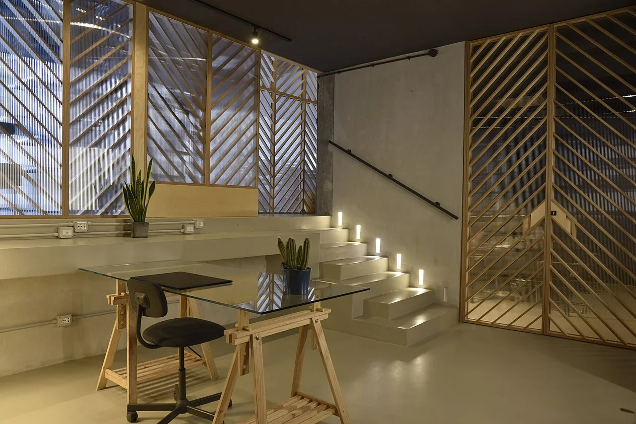 Vista panorámica de un espacio de coworking moderno, con mesas compartidas, sillas de oficina y zonas de trabajo abiertas.