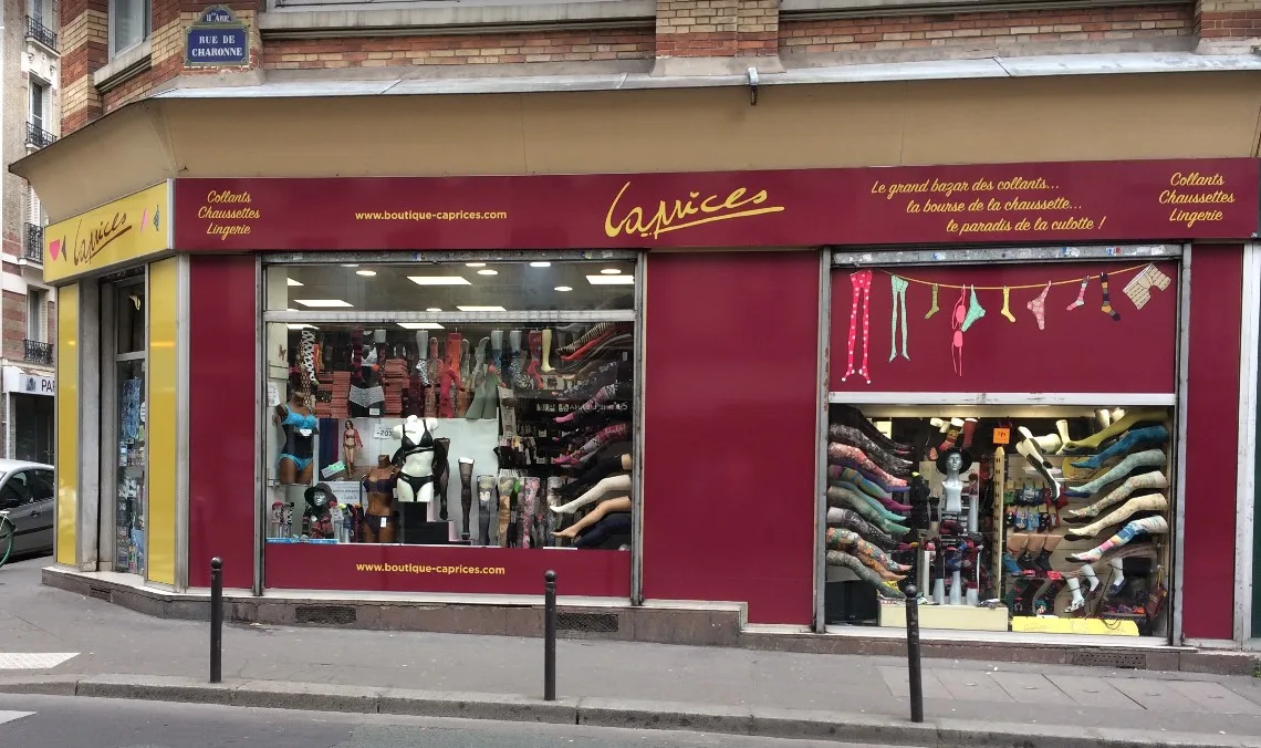 Escaparate de una pequeña boutique de barrio en una calle de París, con productos colocados a la vista del peatón.