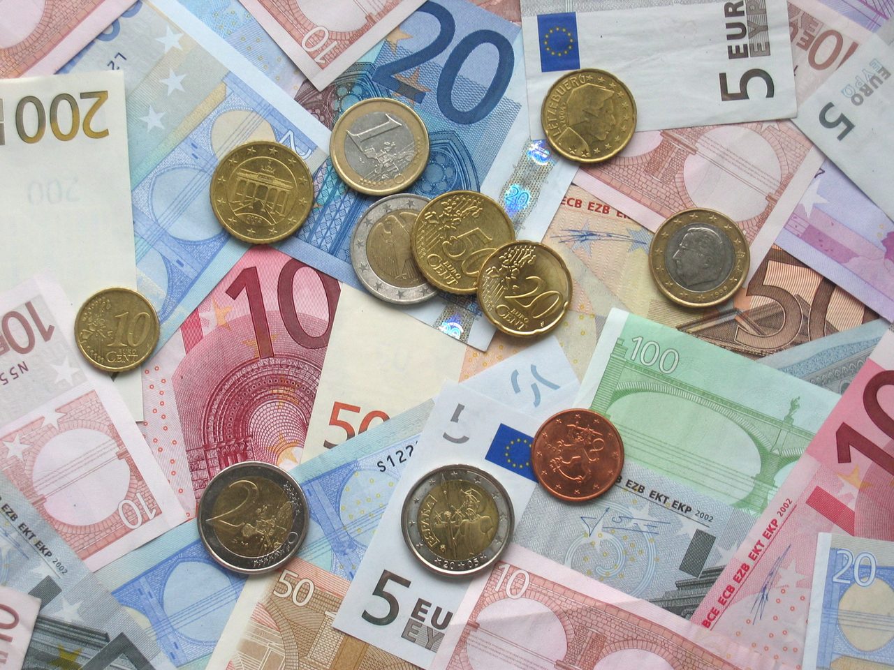 Conjunto de billetes y monedas de euro de distintas denominaciones dispuestos sobre una superficie.