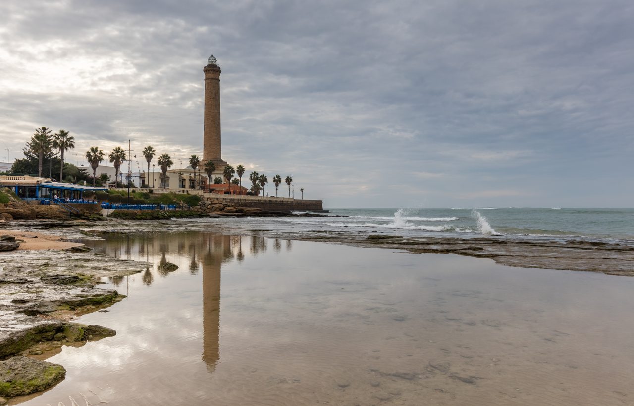 Faro de Chipiona, en Cádiz, torre de 62 metros sobre la costa atlántica andaluza reflejada en la pleamar.