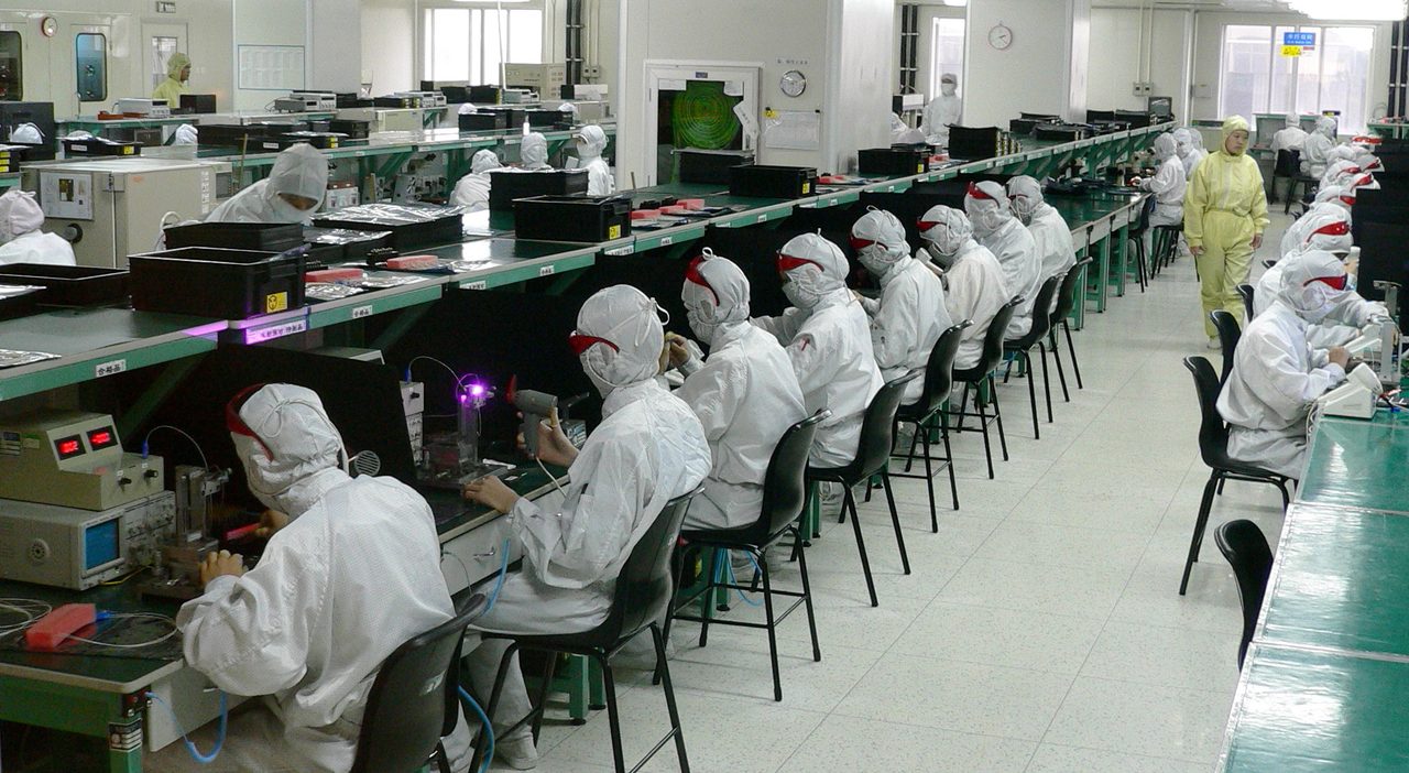 Operarios trabajando en una línea de montaje de una fábrica de electrónica