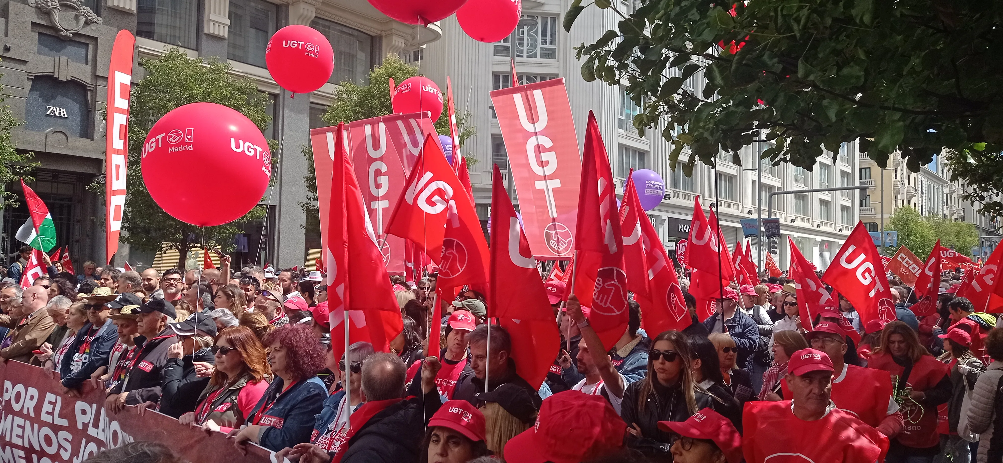 Manifestación del 1 de mayo de 2024 recorriendo la Gran Vía de Madrid, con una densa marea de manifestantes, banderas y pancartas sindicales ocupando toda la anchura de la calle.