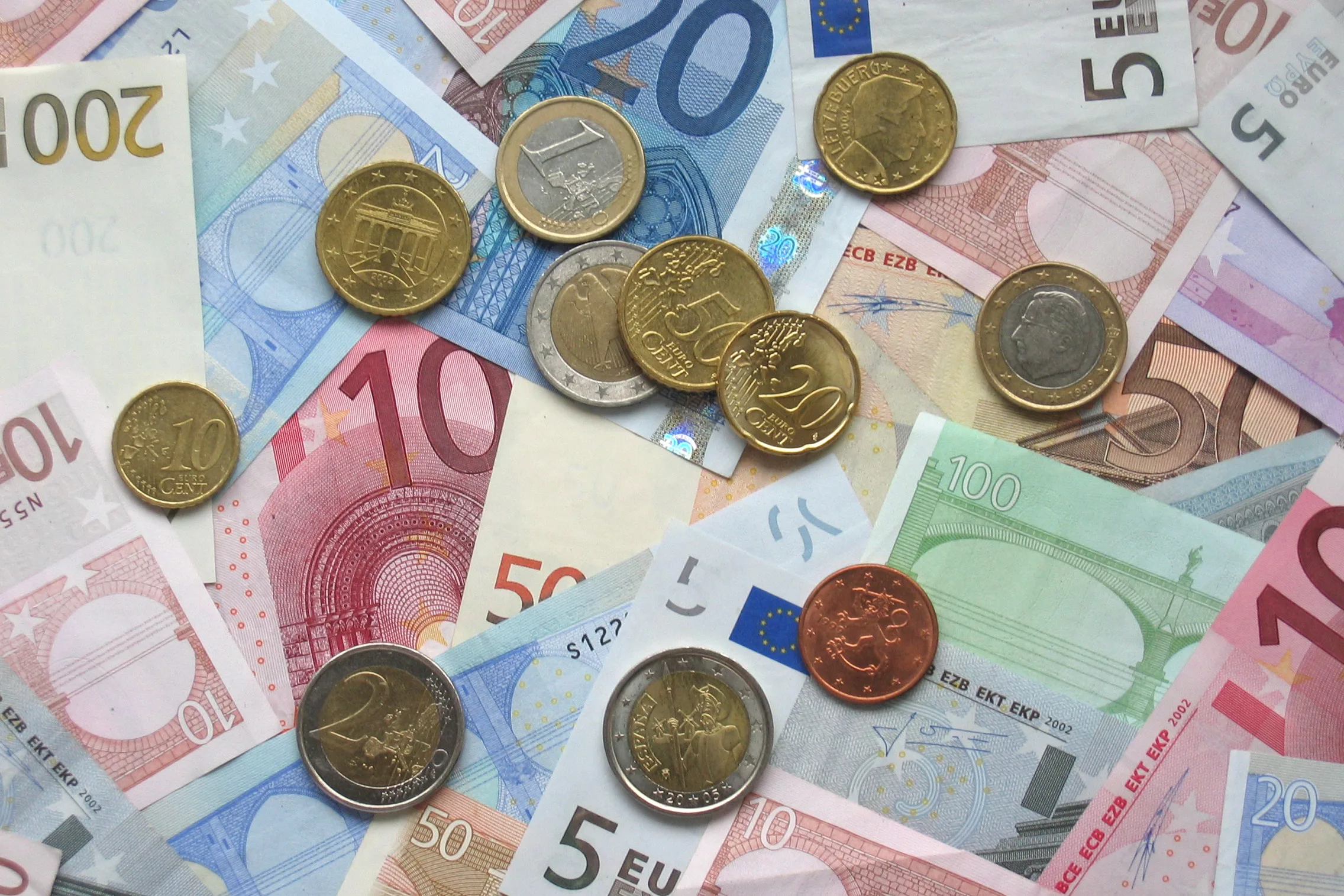Billetes y monedas de euro de distintas denominaciones colocados juntos sobre una superficie.
