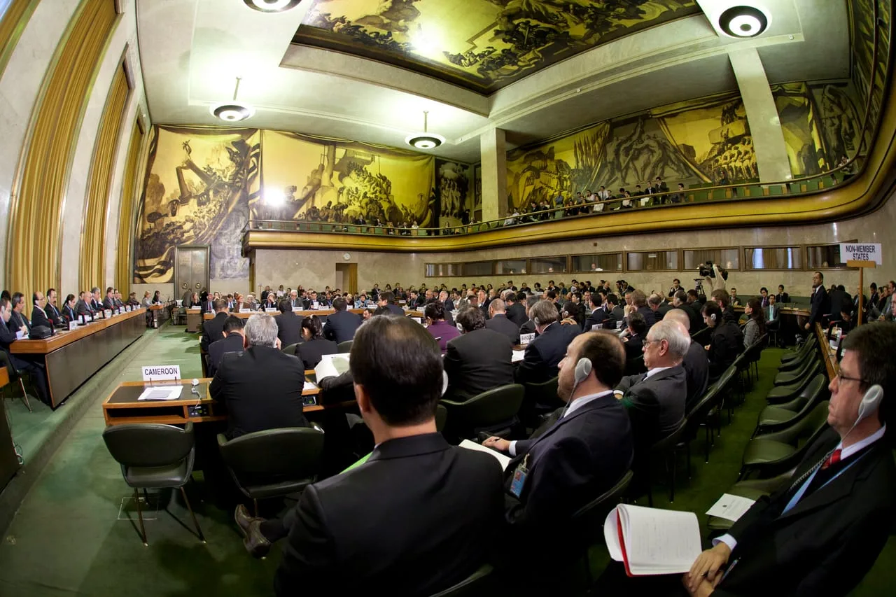 Sesión en la Sala del Consejo del Palacio de las Naciones de Ginebra, con las delegaciones sentadas tras los rótulos de sus países.
