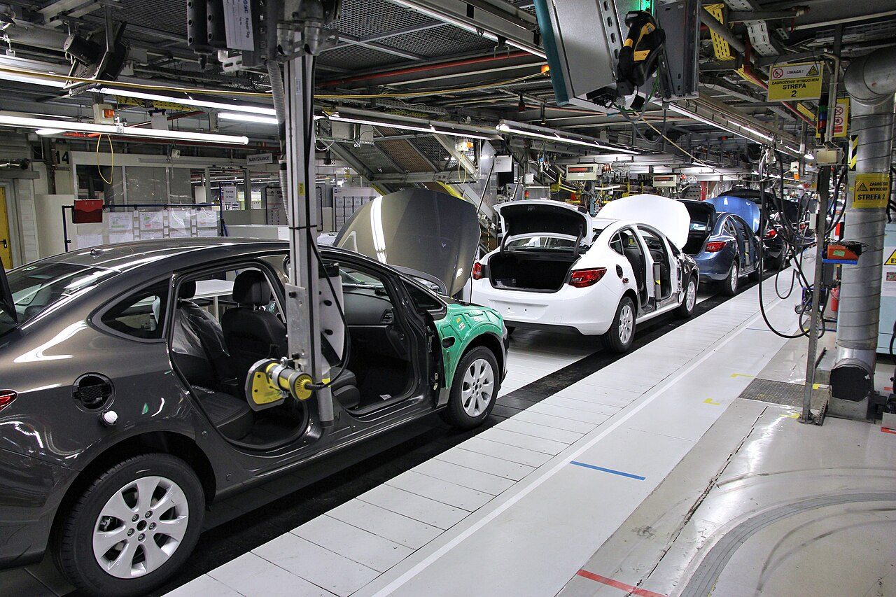 Cadena de montaje de la fábrica Opel en Gliwice: carrocerías del Astra J avanzan por una línea continua con operarios.