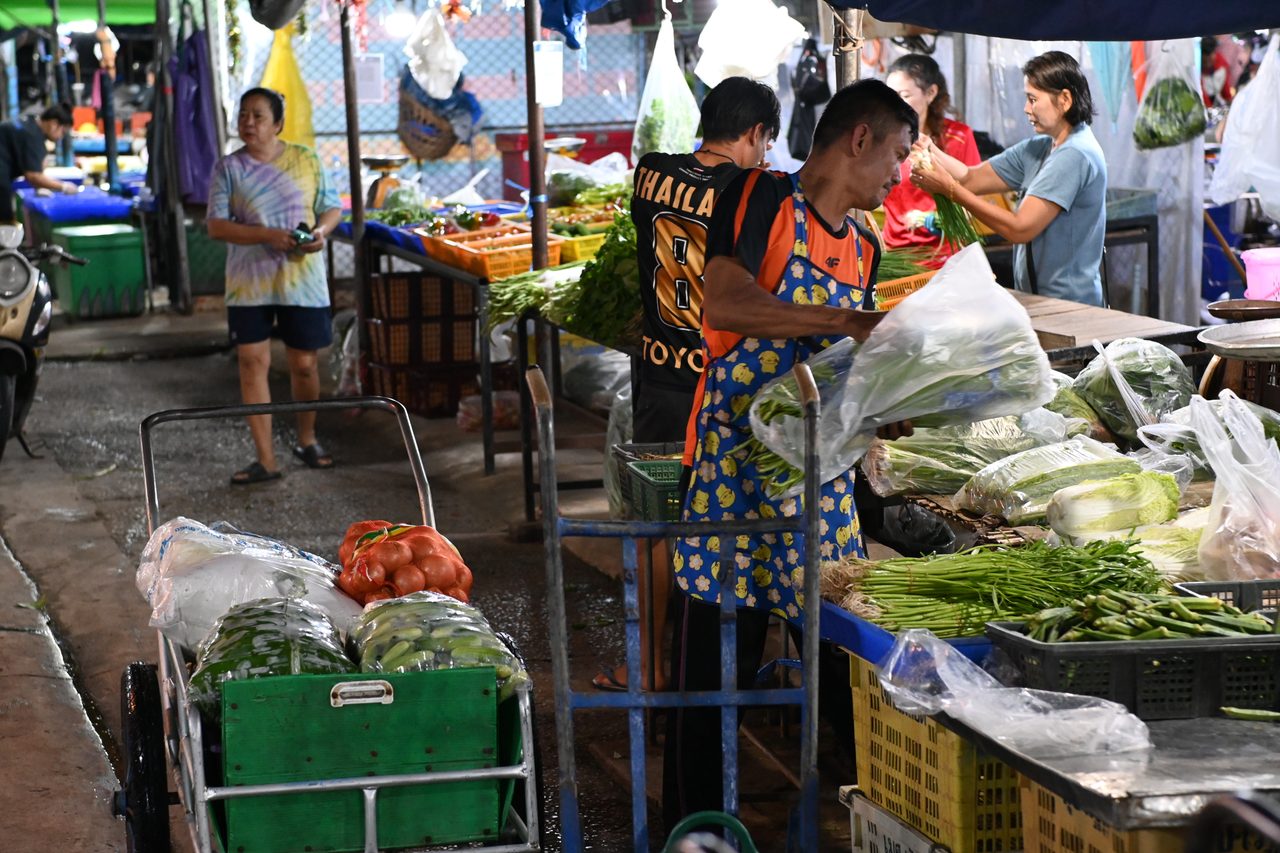 Vendedores colocando verdura fresca en una parada de mercado al aire libre
