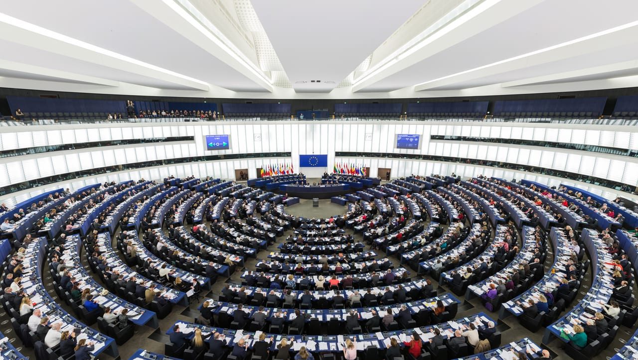 Hemiciclo del Parlamento Europeo en Estrasburgo lleno durante una sesión plenaria, con la bandera de la Unión al fondo.