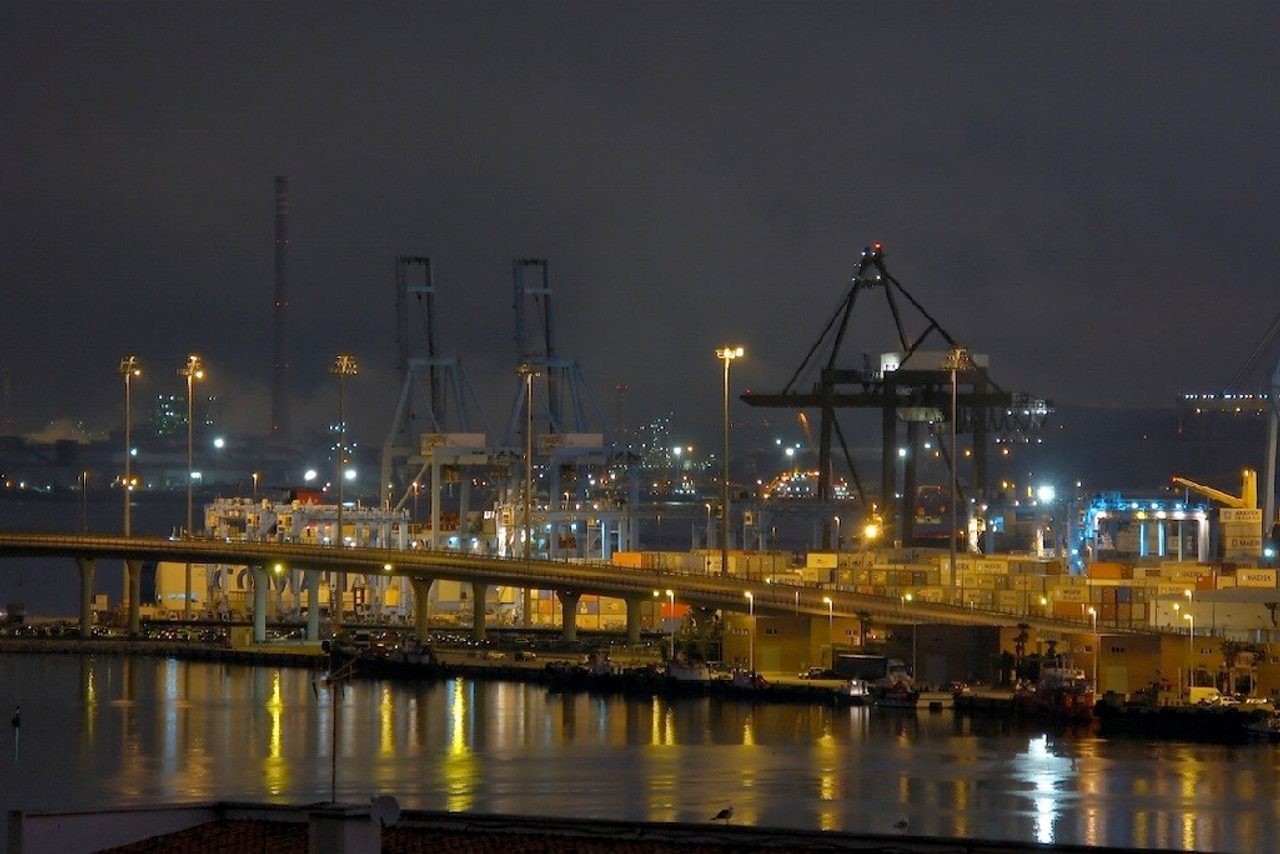 Amanecer en el puerto de Algeciras, con grúas de contenedores recortadas contra el cielo y filas de contenedores apilados en la terminal.
