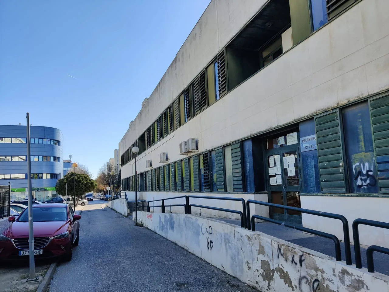 Entrada de un Registro Civil en un edificio administrativo corriente, con el rótulo sobre la puerta y avisos pegados en el cristal.