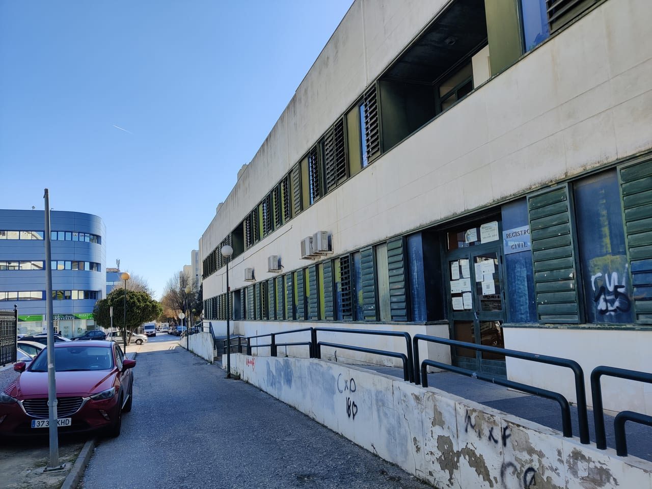 Entrada de un Registro Civil en un edificio administrativo corriente, con el rótulo sobre la puerta y avisos pegados en el cristal.