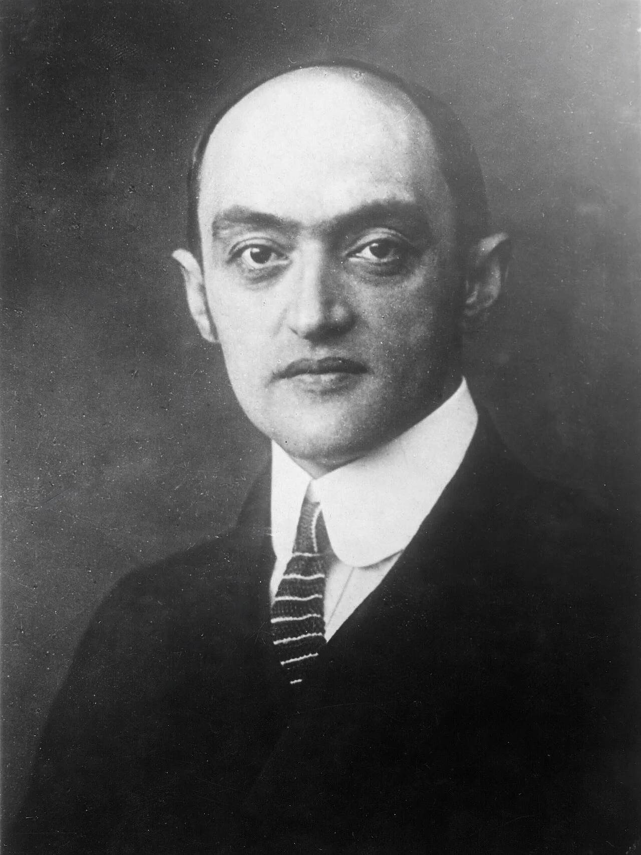 Retrato fotográfico en blanco y negro de Joseph Schumpeter, economista austríaco, en pose formal con traje y corbata.