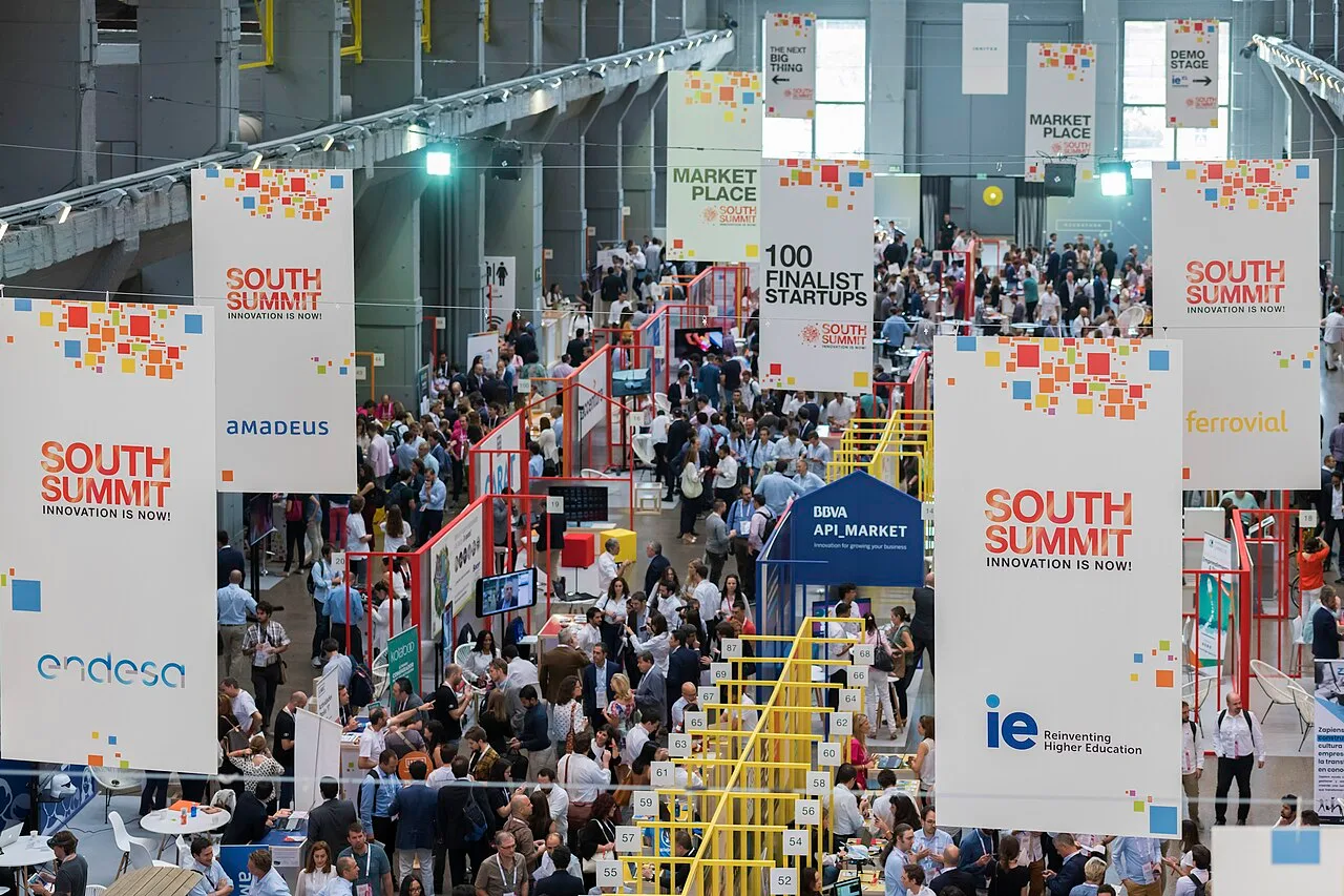 Zona del marketplace de South Summit 2019 en La Nave (Madrid), con stands de startups, asistentes paseando entre los expositores y una gran nave industrial reconvertida como espacio del evento.