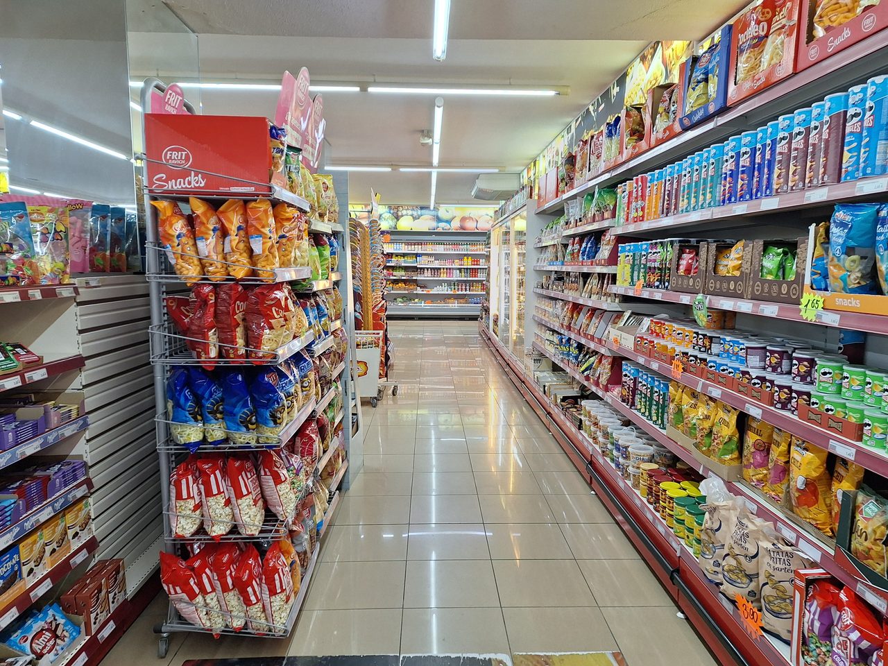 Interior de un supermercado con estanterías llenas de productos de distintas marcas a la venta.