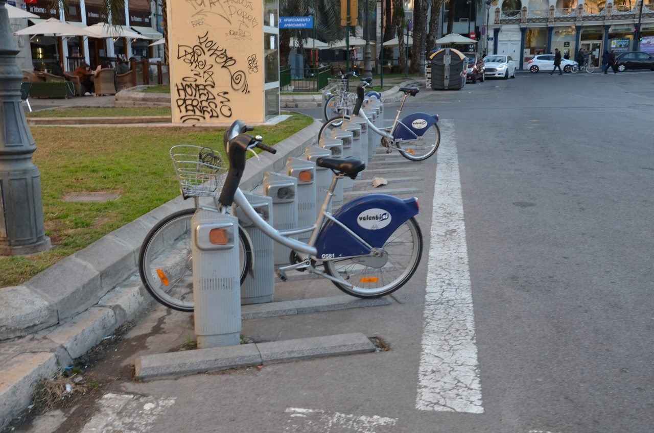 Estación de bicicletas compartidas Valenbisi en una calle de València, con varias bicicletas ancladas en sus puestos.